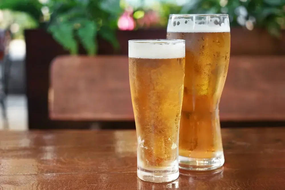 大小兩杯金黃啤酒並排，容量放大時啤酒熱量也等比例增加